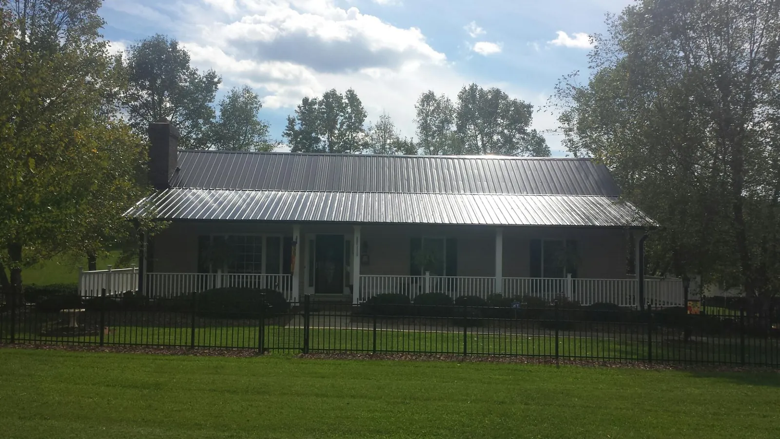 Gray metal roof on a brick ranch with a full width front porch — Gutter Guard Installation work by our crew in Ashland